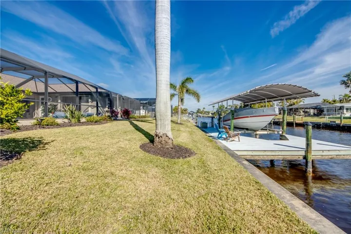 View of dock featuring a water view, a yard, and a lanai