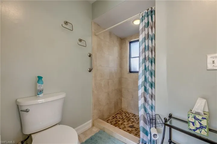 Bathroom featuring a shower with curtain, tile patterned floors, and toilet