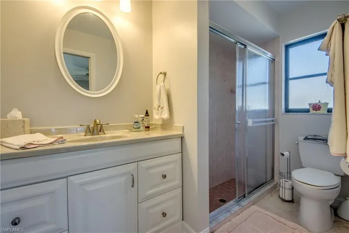 Bathroom with a shower with door, vanity, and toilet