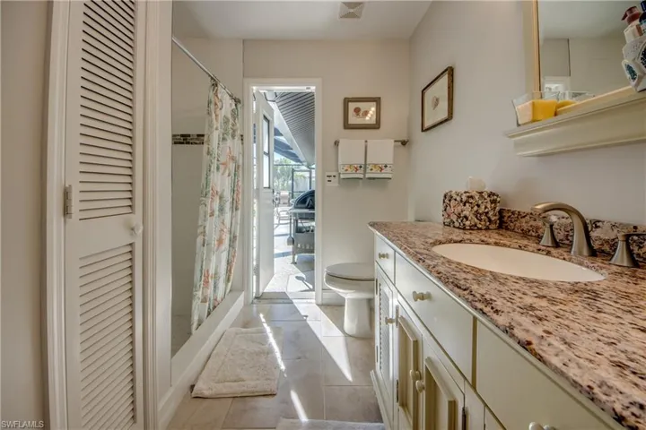 Bathroom with a shower with curtain, tile patterned floors, vanity, and toilet