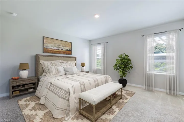 Bedroom featuring light carpet and multiple windows