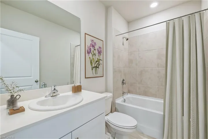 Full bathroom with shower / bath combo with shower curtain, vanity, and toilet
