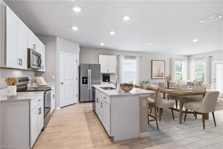 Kitchen featuring white cabinetry, sink, a kitchen island with sink, appliances with stainless steel finishes, and light wood-type flooring