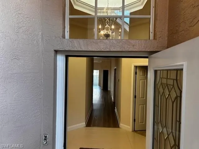 Hallway featuring a textured wall, a chandelier, and a towering ceiling