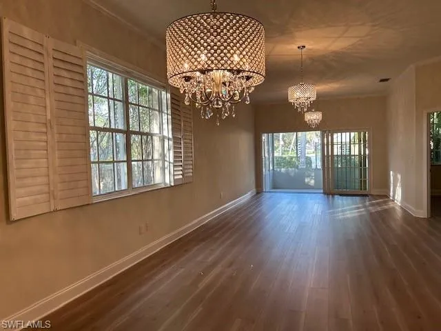 Unfurnished dining area with crown molding, a chandelier, and dark wood-style floors