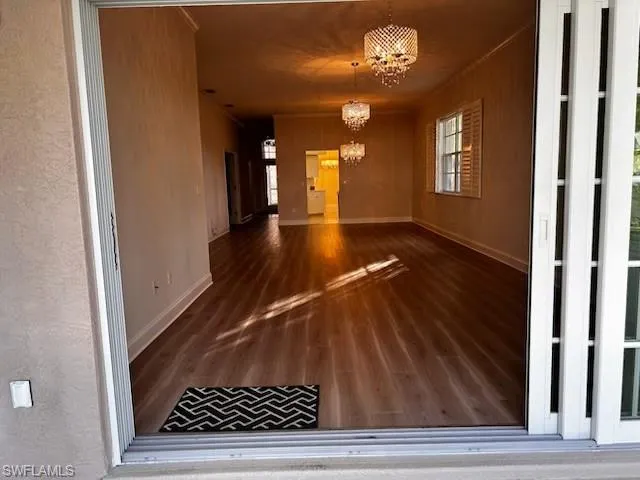 Unfurnished dining area featuring a chandelier, dark wood-type flooring, and ornamental molding