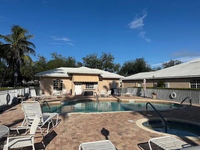 Community pool featuring fence, a patio area, and a hot tub