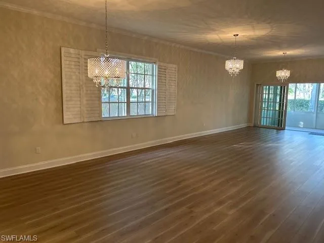 Unfurnished dining area with a chandelier, dark wood finished floors, and ornamental molding