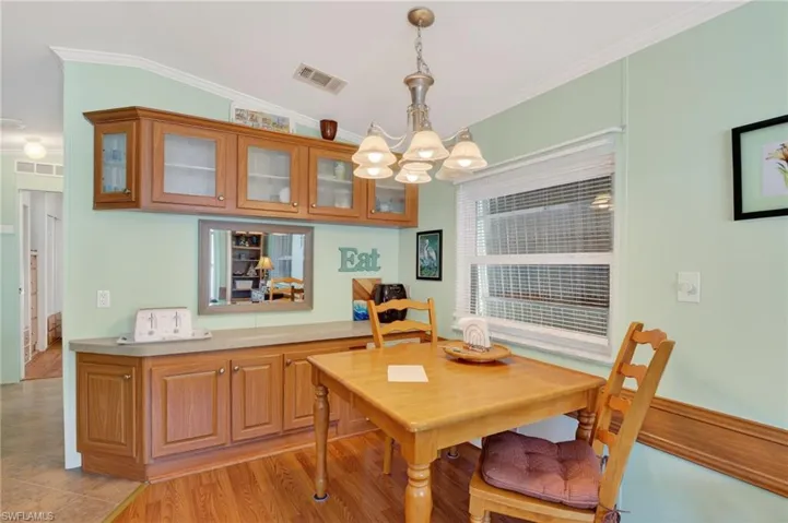 Dining room with ornamental molding, a chandelier, and light wood-style flooring