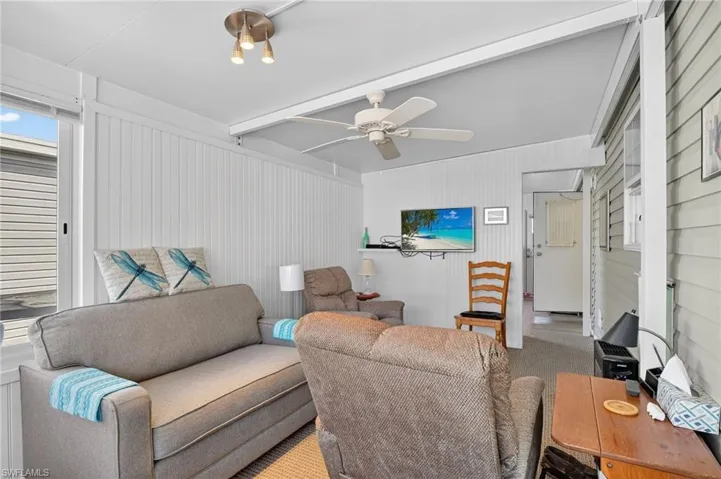 Carpeted living area featuring beamed ceiling and ceiling fan