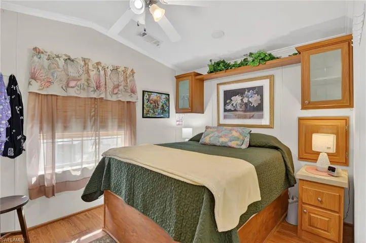 Bedroom with crown molding, a ceiling fan, lofted ceiling, and wood finished floors