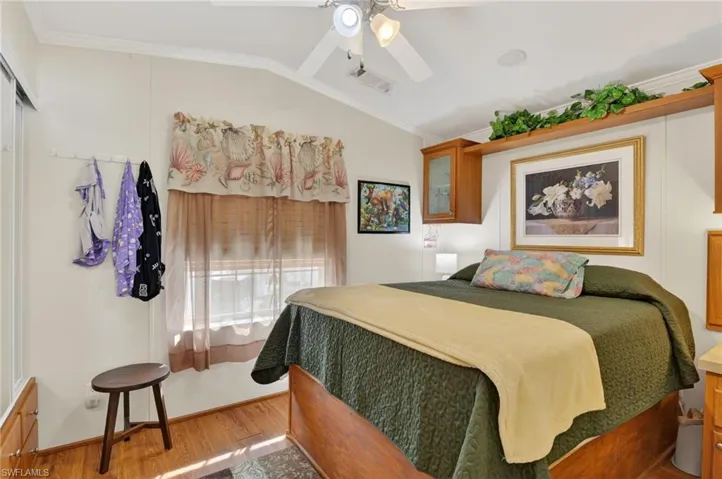Bedroom featuring crown molding, wood finished floors, vaulted ceiling, and ceiling fan