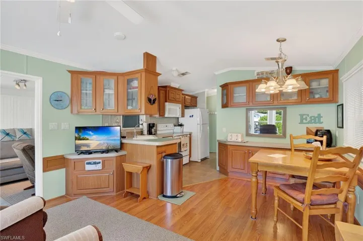 Living room featuring ornamental molding, a chandelier, light wood finished floors, lofted ceiling, and ceiling fan