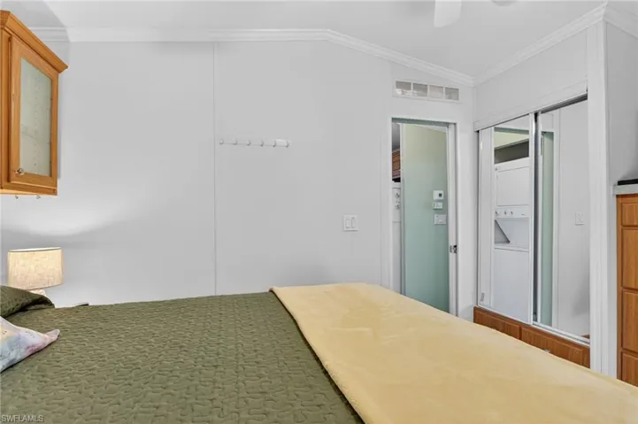 Bedroom with ornamental molding, a ceiling fan, and stacked washer / dryer