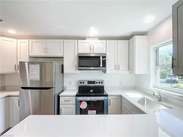 Kitchen featuring stainless steel appliances, sink, and white cabinetry