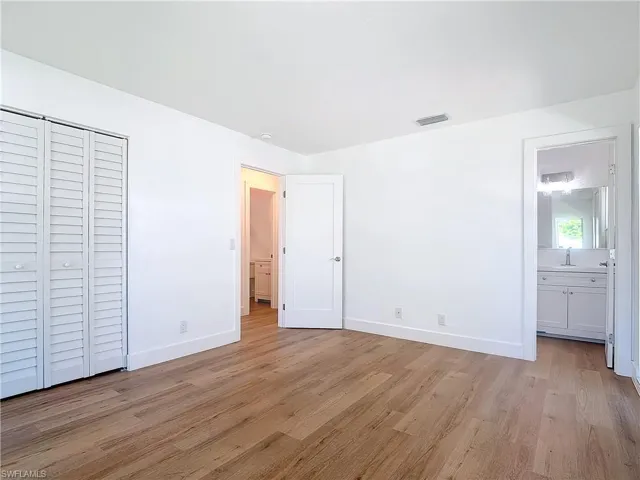 Unfurnished bedroom featuring light hardwood / wood-style flooring, ensuite bath, and sink