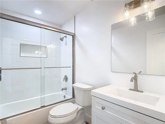 Full bathroom featuring enclosed tub / shower combo, vanity, and toilet