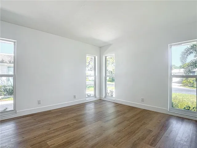 Unfurnished room featuring dark hardwood / wood-style floors and a wealth of natural light