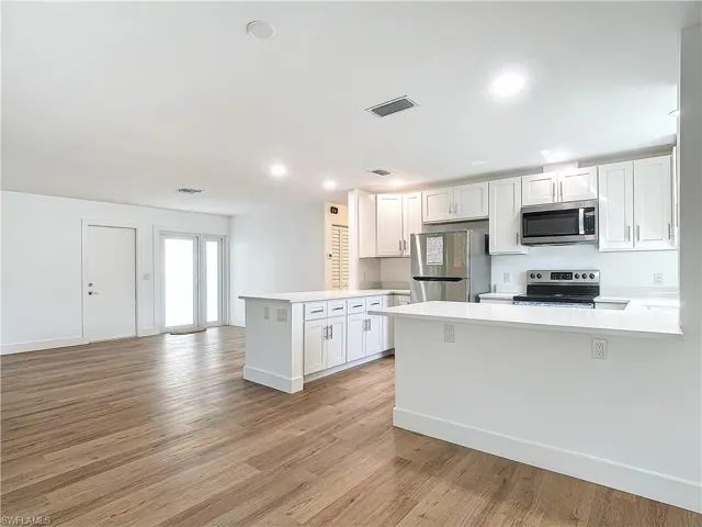 Kitchen with kitchen peninsula, white cabinetry, and stainless steel appliances