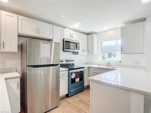 Kitchen with light hardwood / wood-style flooring, white cabinetry, appliances with stainless steel finishes, and sink
