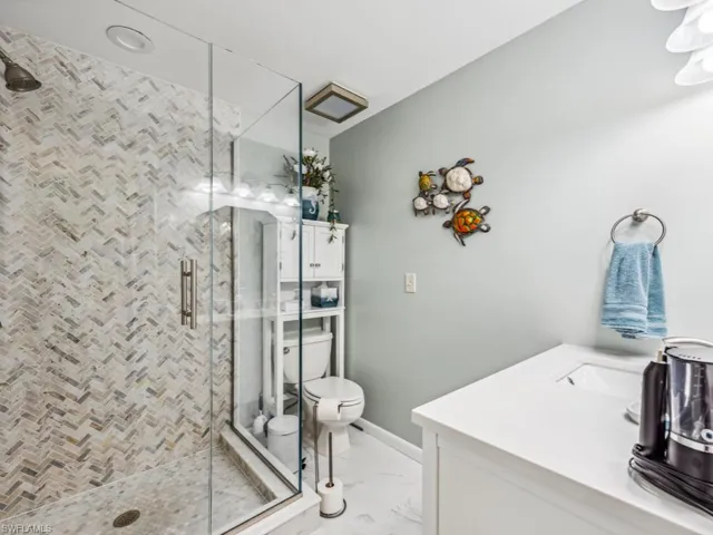 Bathroom featuring vanity, toilet, tile patterned flooring, and a shower with shower door