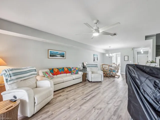 Living room featuring light wood-type flooring and ceiling fan with notable chandelier