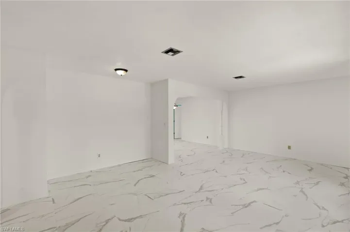 Living room featuring baseboards, visible vents, and marble-like tile finish floor