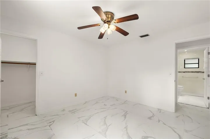 Guest bedroom with marble finish floor, baseboards, a ceiling fan, and visible vents