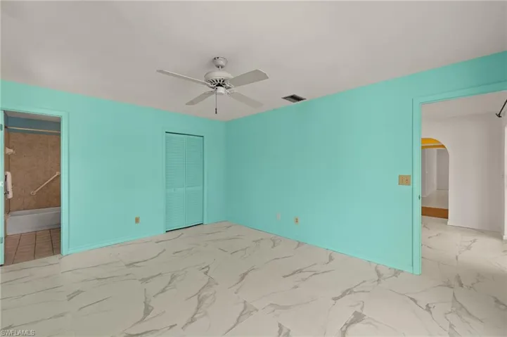 Unfurnished bedroom featuring marble finish floor, baseboards, arched walkways, and a closet