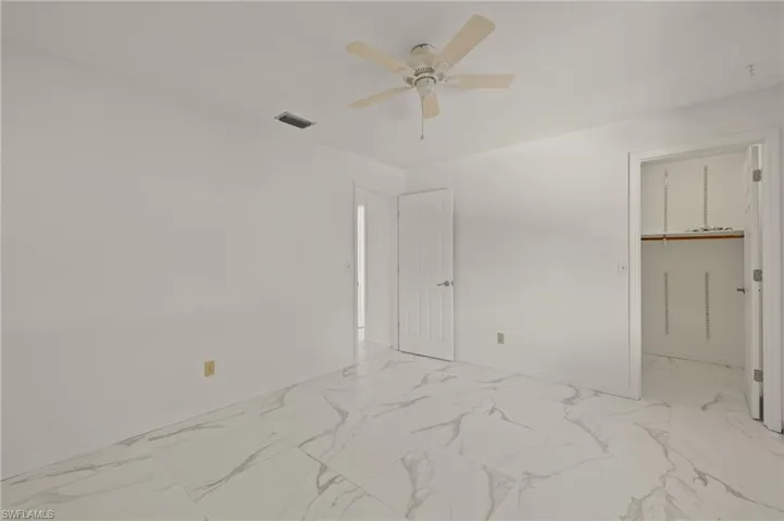 Unfurnished bedroom with baseboards, visible vents, marble-like tile finish floor, and ceiling fan