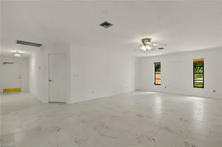 Unfurnished room with marble-like tile finish floor, baseboards, a ceiling fan, and visible vents