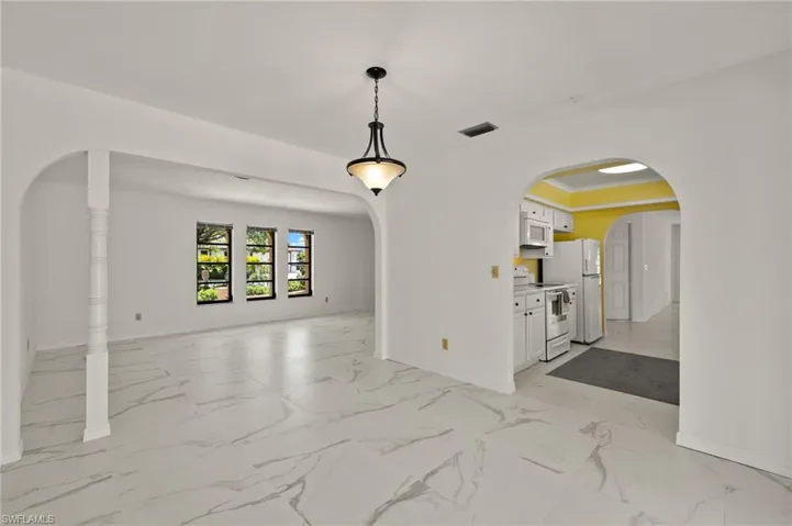 Unfurnished room with arched walkways, visible vents, marble finish floor, and baseboards