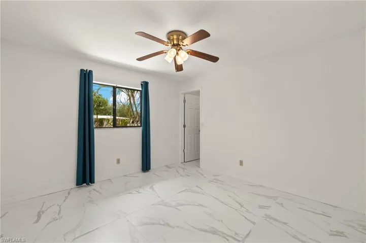 Guest Bedroom with ceiling fan, baseboards, and marble-like tile finish floor