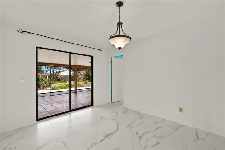 Dining area with sliders to lanai featuring marble-like tile finish floor and baseboards