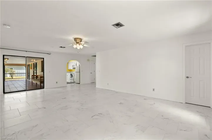 Spare room featuring arched walkways, baseboards, visible vents, a ceiling fan, and marble finish floor