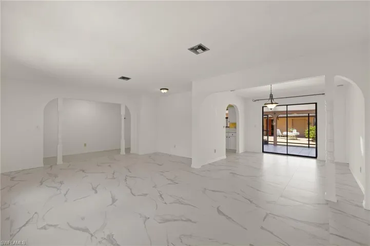 Family room with arched walkways, visible vents, marble -like tile finish floor, and baseboards