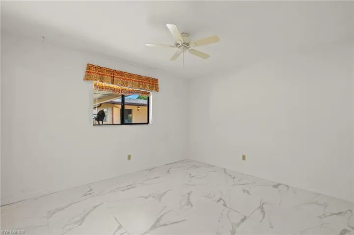 Guest bedroom featuring marble-like tile finish floor, baseboards, and ceiling fan