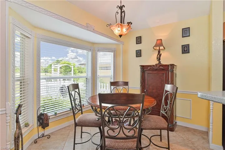 Bay window with horizontal blinds, decorative trim, and tiled flooring