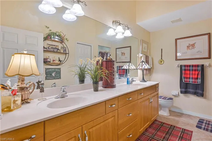Double vanity featuring integrated sinks, light-toned countertops, and wood-finish cabinetry with silver-tone hardware