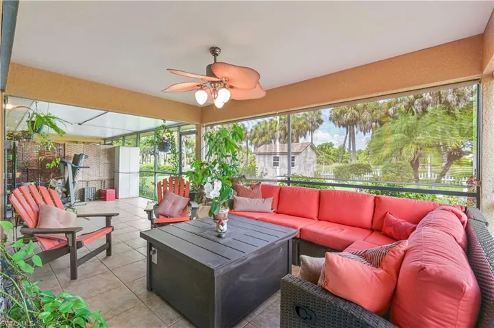 Expansive screened patio featuring a ceiling fan with integrated lighting, tiled flooring, and a broad exterior backdrop of tropical foliage