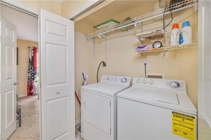 Dedicated laundry area featuring a washer and dryer, practical wire shelving, and neutral wall paint