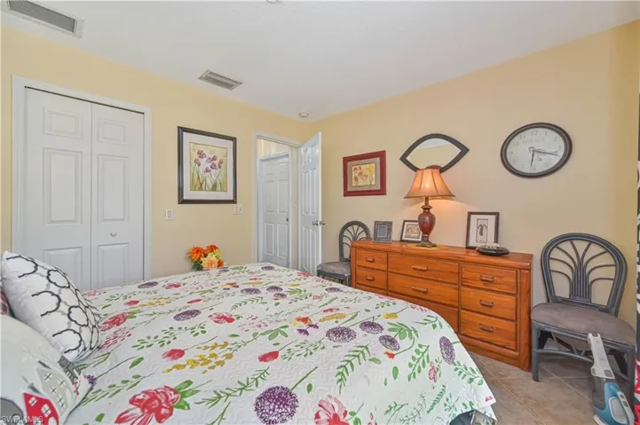 Bedroom featuring light-toned walls, tile flooring, and multiple white panel doors