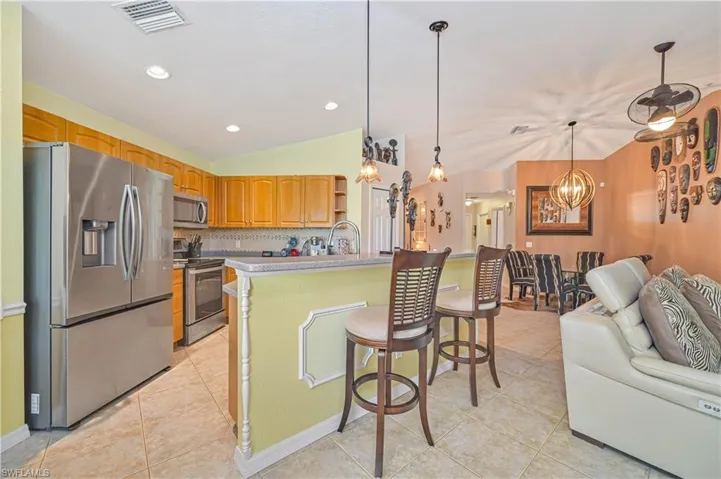 Kitchen featuring stainless steel appliances, wood cabinetry, a tiled backsplash, and recessed lighting