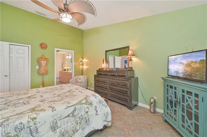 Spacious bedroom featuring tile flooring, a ceiling fan with integrated lighting, and a closet with bifold doors