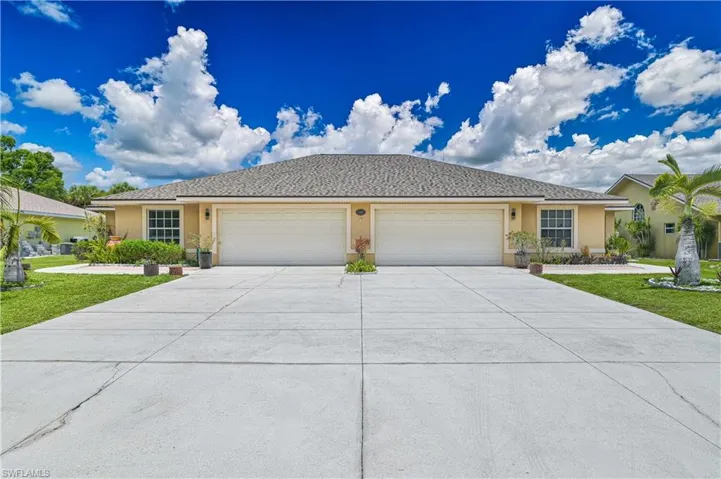 Duplex exterior featuring a tan stucco finish and a gray shingle roof