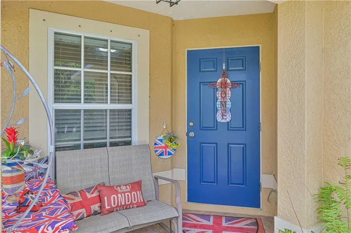 Recessed entry featuring a paneled blue entry door, textured stucco walls, and a large multi-pane window