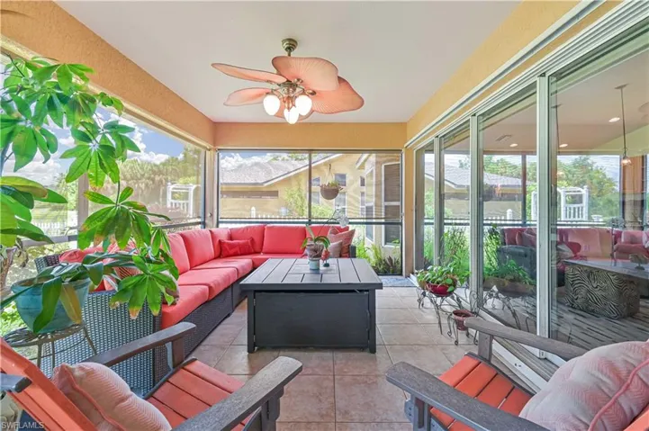 Screened lanai featuring large format tile flooring, a textured ceiling with a flush-mount ceiling fan, and extensive sliding glass doors