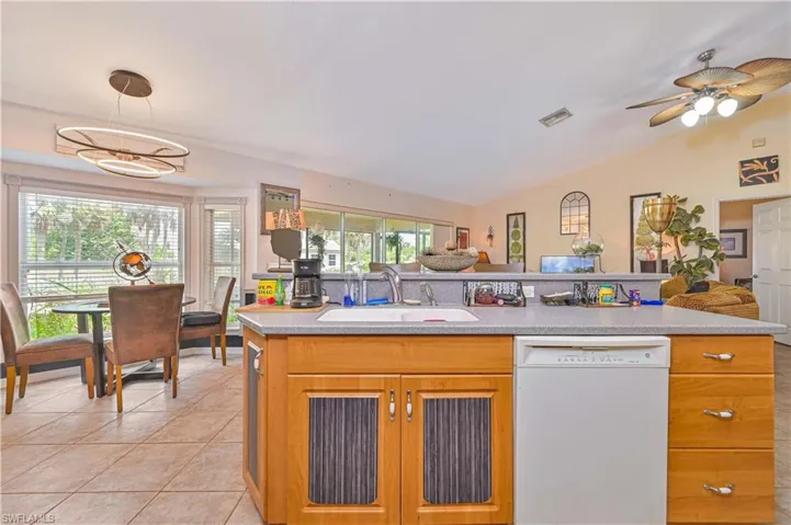 Kitchen island with integrated sink and dishwasher, wood-finish cabinetry, and solid surface countertop