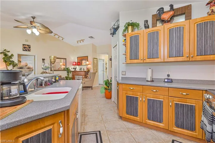 Kitchen featuring light wood cabinetry with corrugated inserts, grey countertops, and a double basin sink with a chrome faucet