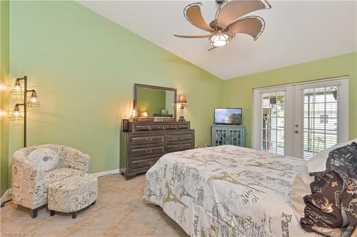 Vaulted ceiling room featuring tiled flooring, French doors, and a ceiling fan with integrated lighting